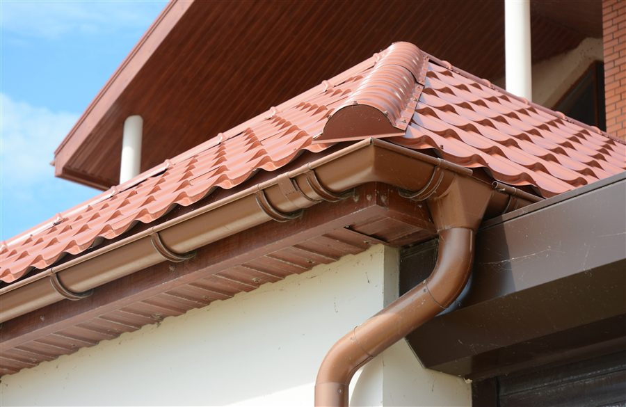 Rain gutter and downspout installation on a tiled roof