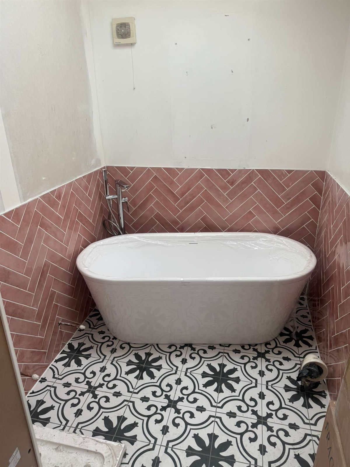 Freestanding bath with pink herringbone tiling